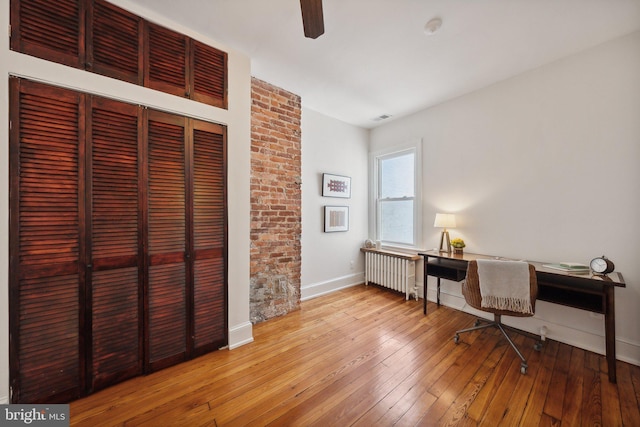 office area featuring radiator, ceiling fan, and hardwood / wood-style floors