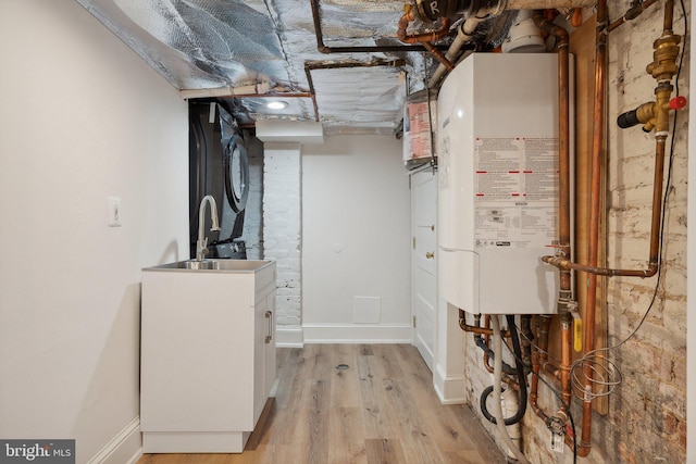 utility room with stacked washing maching and dryer, sink, and water heater