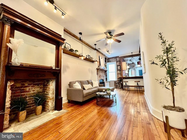 living room featuring ceiling fan, light hardwood / wood-style floors, and a fireplace