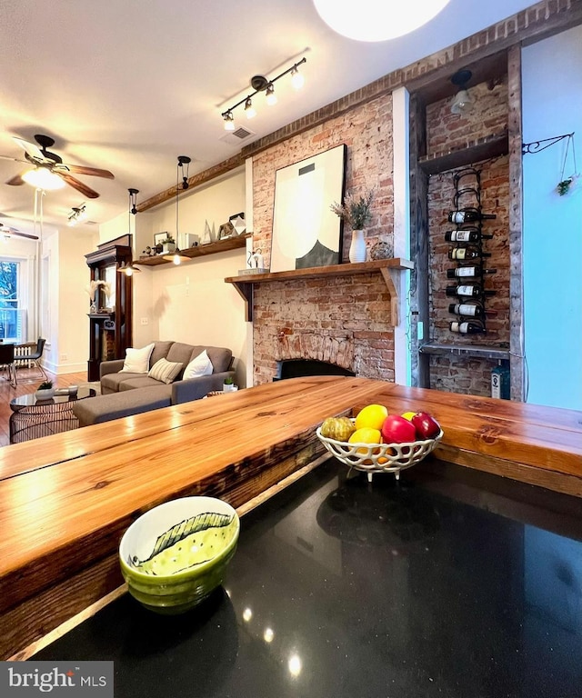 interior space with a fireplace, ceiling fan, and brick wall