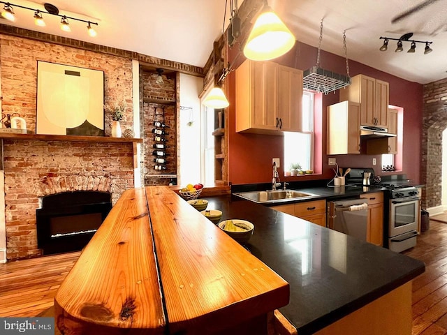 kitchen with brick wall, stainless steel appliances, sink, light brown cabinets, and light hardwood / wood-style flooring