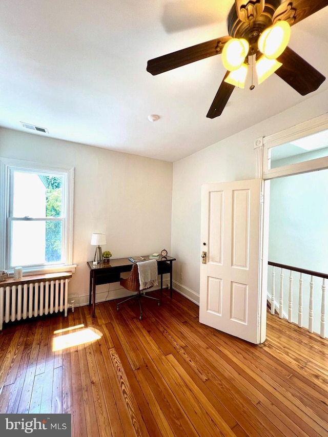 unfurnished room with radiator heating unit, ceiling fan, and wood-type flooring