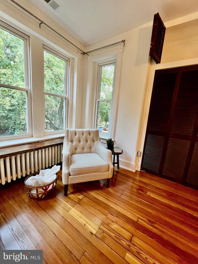 sitting room with a wealth of natural light, radiator heating unit, and wood-type flooring