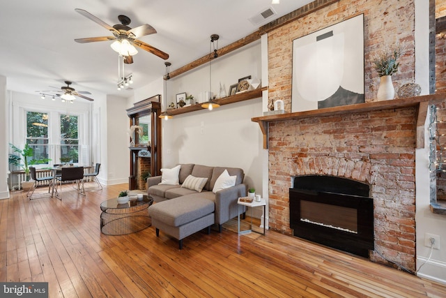 living room featuring ceiling fan, light hardwood / wood-style flooring, and a brick fireplace