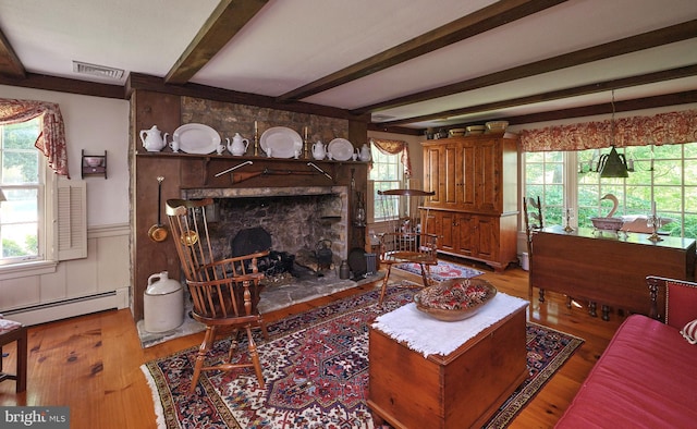 living room featuring a fireplace, beam ceiling, hardwood / wood-style flooring, and baseboard heating