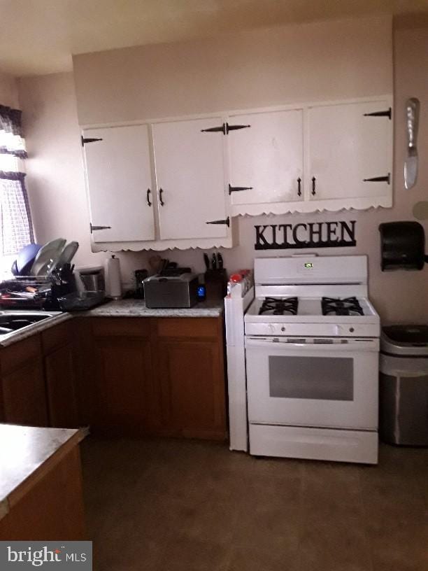 kitchen featuring white cabinetry, white gas range, and sink