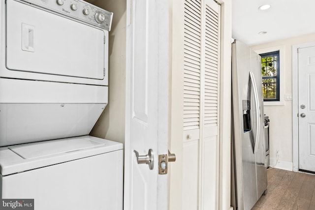 laundry area with stacked washer and dryer and light hardwood / wood-style flooring