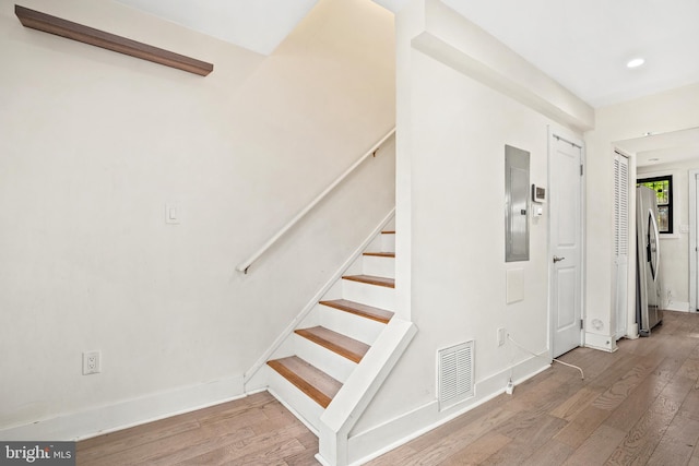 staircase featuring wood-type flooring and electric panel