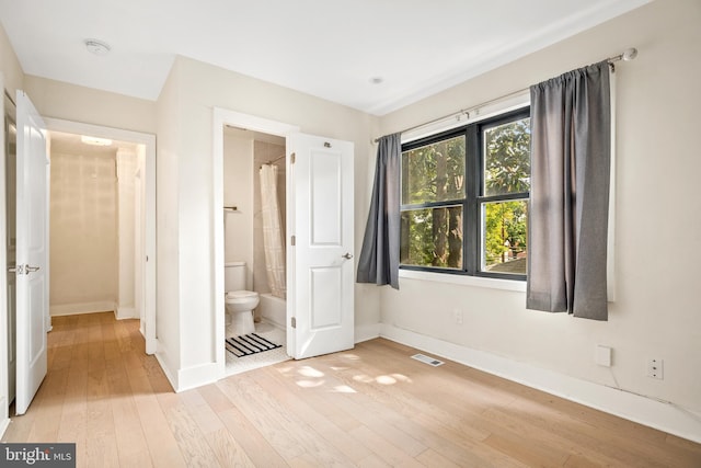 unfurnished bedroom featuring light wood-type flooring and ensuite bathroom