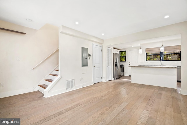 unfurnished living room with electric panel and light hardwood / wood-style flooring