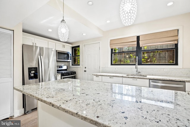 kitchen featuring stainless steel appliances, sink, decorative light fixtures, light hardwood / wood-style floors, and white cabinetry