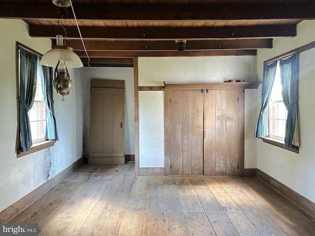 unfurnished bedroom with beamed ceiling, light hardwood / wood-style floors, and wooden ceiling