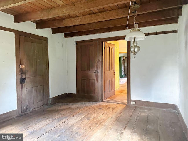 empty room featuring beam ceiling, hardwood / wood-style flooring, and wood ceiling