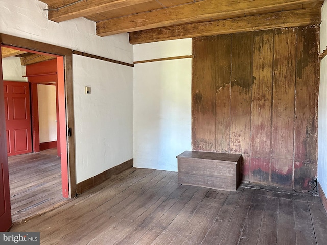 unfurnished room with beamed ceiling and dark hardwood / wood-style flooring