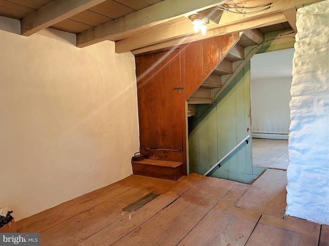 stairway featuring beamed ceiling and a baseboard radiator