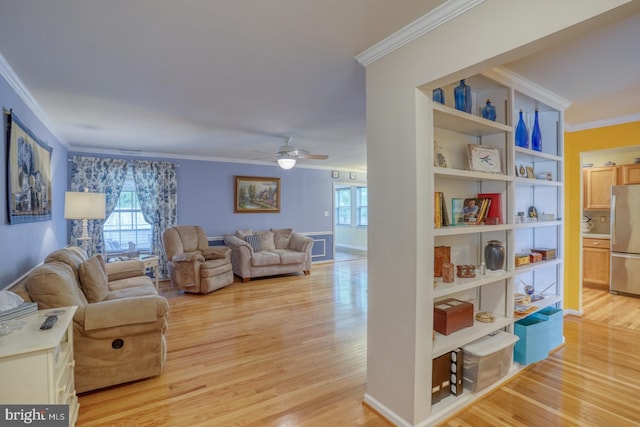 living room featuring ceiling fan, light hardwood / wood-style floors, and crown molding