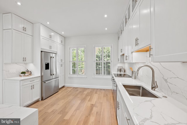 kitchen with light stone counters, sink, white cabinets, and stainless steel appliances