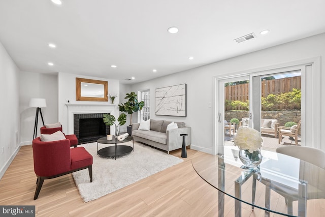 living room featuring light hardwood / wood-style floors and a brick fireplace