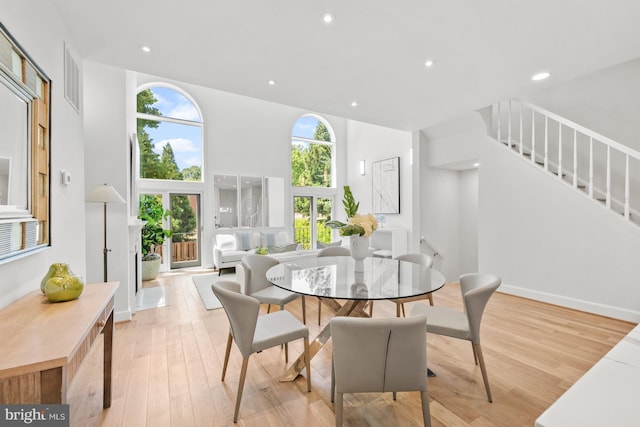 dining space featuring light hardwood / wood-style floors and a towering ceiling