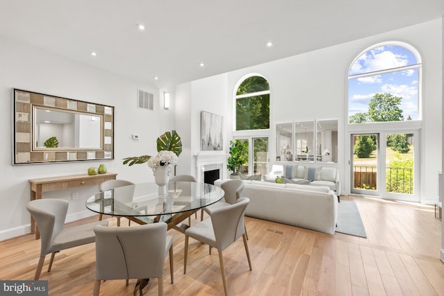 dining room featuring light hardwood / wood-style flooring and a towering ceiling