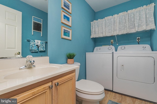 bathroom with wood-type flooring, vanity, toilet, and washing machine and clothes dryer