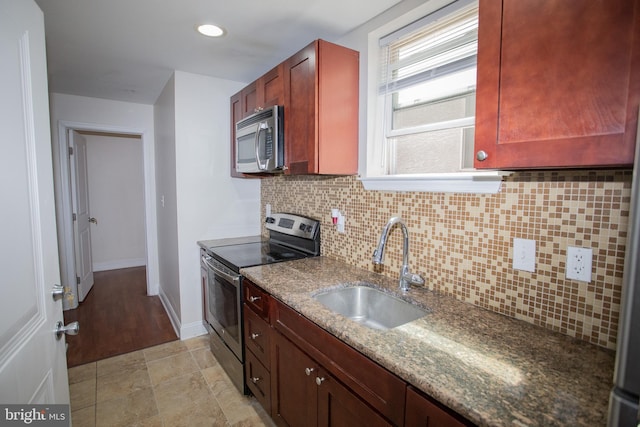 kitchen with sink, black electric range oven, backsplash, dark stone counters, and light wood-type flooring