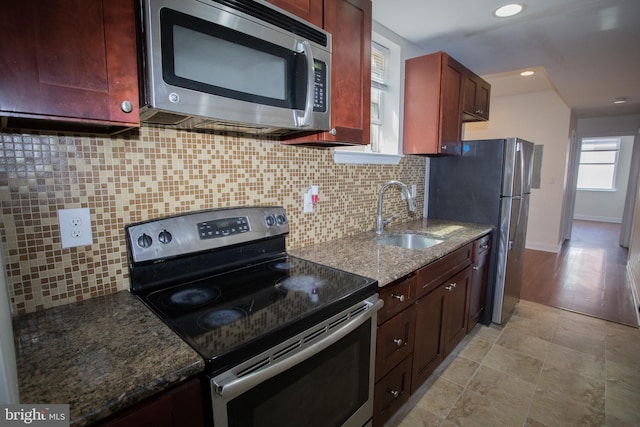 kitchen with dark stone counters, decorative backsplash, sink, and stainless steel appliances