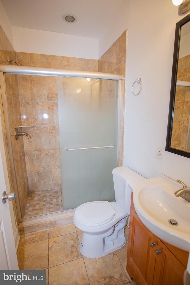 bathroom featuring vanity, a shower with shower door, and toilet