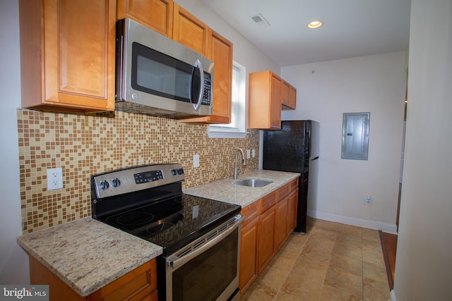 kitchen with electric panel, light stone counters, sink, and appliances with stainless steel finishes