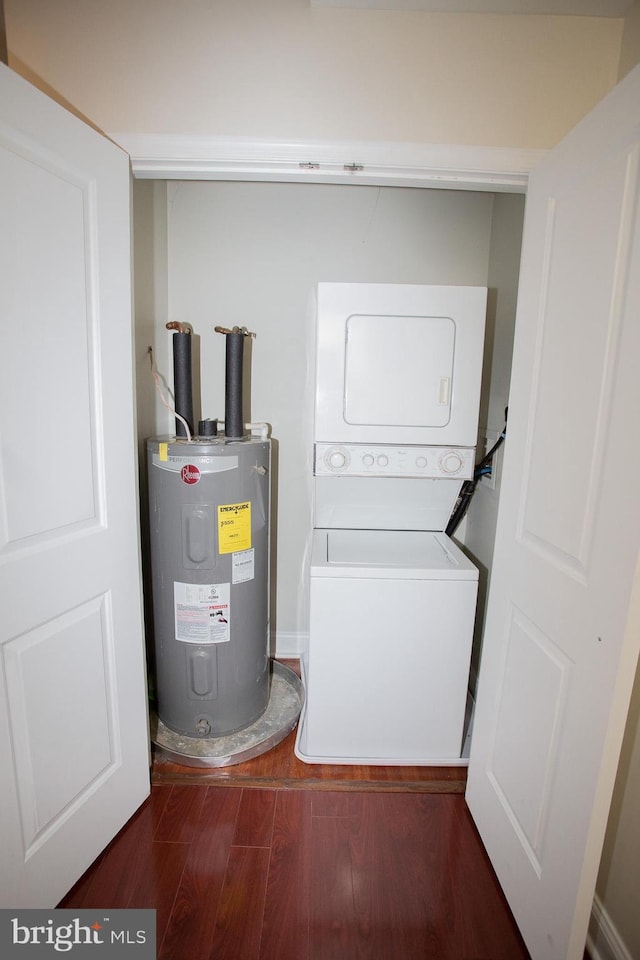 laundry room with electric water heater, stacked washer / dryer, and dark wood-type flooring