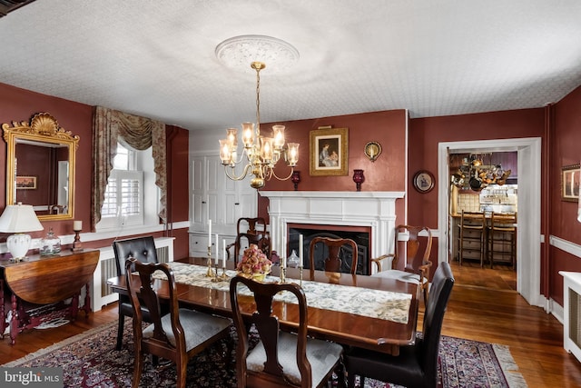 dining room with a textured ceiling, dark wood-type flooring, and an inviting chandelier