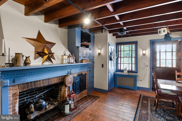 kitchen featuring beamed ceiling, a fireplace, radiator heating unit, and blue cabinetry