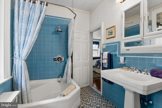 bathroom with sink, shower / bath combination with curtain, and tile walls