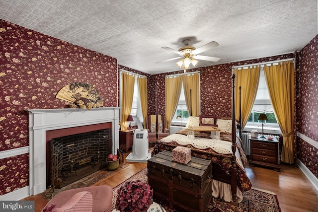 bedroom featuring multiple windows, ceiling fan, wood-type flooring, and a textured ceiling