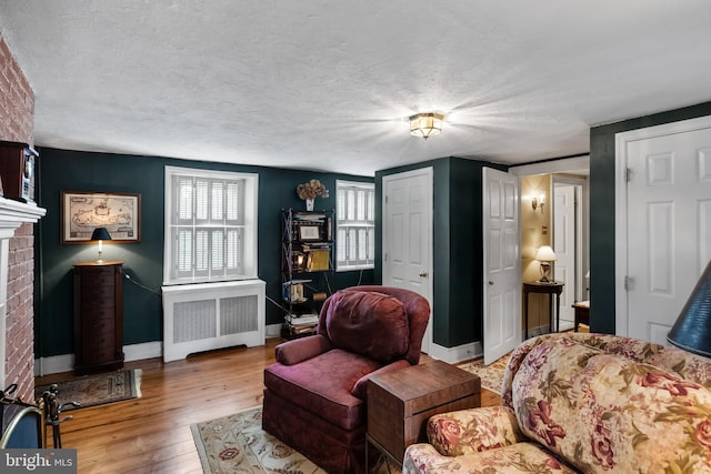 living area with a textured ceiling, light hardwood / wood-style floors, radiator heating unit, and a fireplace