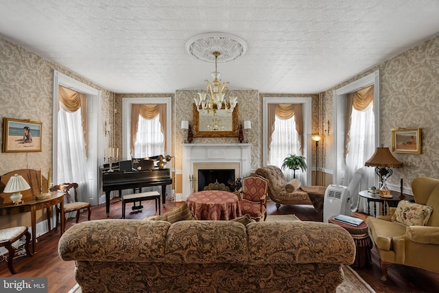 living room with wood-type flooring, a textured ceiling, an inviting chandelier, and a healthy amount of sunlight