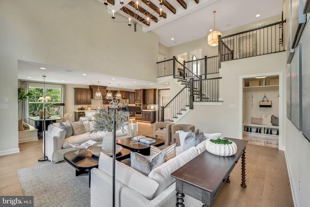 living room featuring beam ceiling, an inviting chandelier, light hardwood / wood-style flooring, and high vaulted ceiling