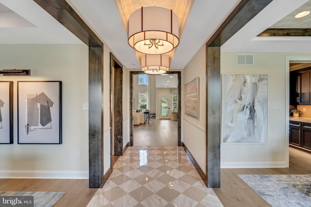 corridor with light hardwood / wood-style floors and a tray ceiling