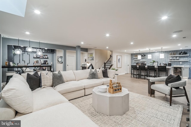 living room featuring bar area, light wood-type flooring, and wine cooler