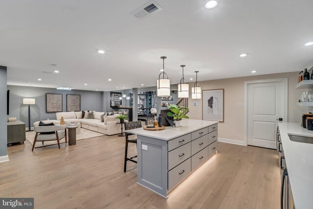 kitchen featuring pendant lighting, sink, light hardwood / wood-style flooring, decorative backsplash, and gray cabinets