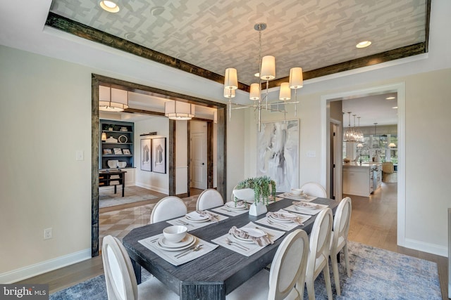 dining room featuring hardwood / wood-style floors, a raised ceiling, sink, and a chandelier