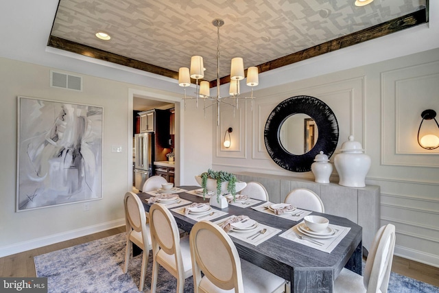 dining space featuring a tray ceiling, an inviting chandelier, and hardwood / wood-style flooring