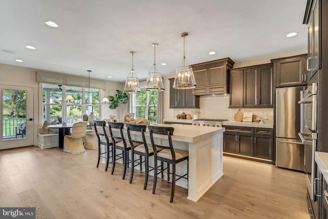 kitchen featuring dark brown cabinets, a center island, stainless steel appliances, and light hardwood / wood-style flooring