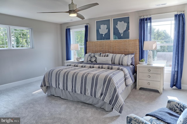 bedroom with multiple windows, light carpet, and ceiling fan