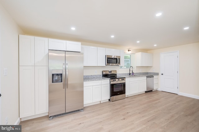 kitchen featuring white cabinets, light wood-type flooring, sink, and appliances with stainless steel finishes