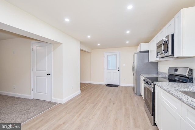 kitchen with light hardwood / wood-style floors, light stone counters, white cabinetry, and appliances with stainless steel finishes