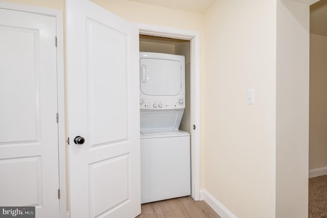 clothes washing area with stacked washer / drying machine and light hardwood / wood-style floors