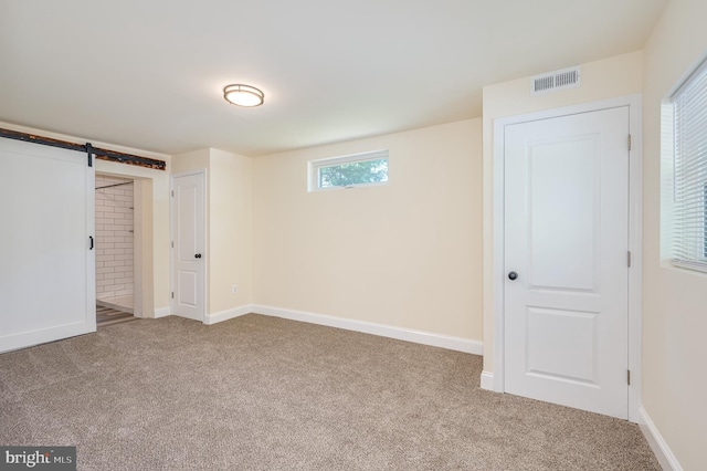 unfurnished bedroom featuring carpet and a barn door