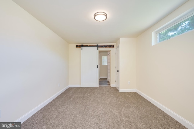 carpeted empty room with a barn door