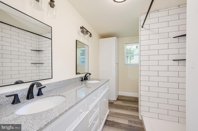 bathroom featuring hardwood / wood-style flooring, vanity, and a tile shower